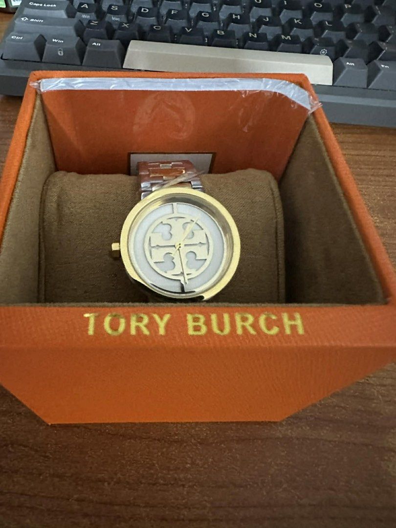 Tory Burch Watch (Category: Women's Watches) located in Quezon City. Submitted by raymonet (Listing ID 1435574626, Image 1). Description: - Tory Burch watch - Gold-tone bezel - Two-tone stainless steel band - Tory Burch logo on watch face - Includes original box and shopping bag - Perfect for any occasion.
