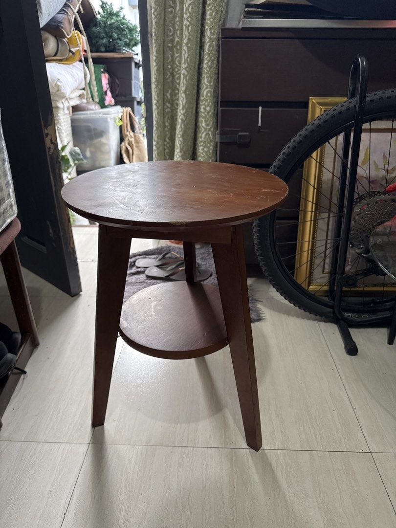 Wooden Side Table with Shelf (Category: Tables & Sets) located in Quezon City. Submitted by elektra0111 (Listing ID 1435713943, Image 1). Description: - Round tabletop - Lower shelf for storage - Classic design with angled legs - Warm brown finish - Versatile use: bedside table, accent piece - Practical and stylish - dimensions of the table Diameter 40cm Height 54cm.