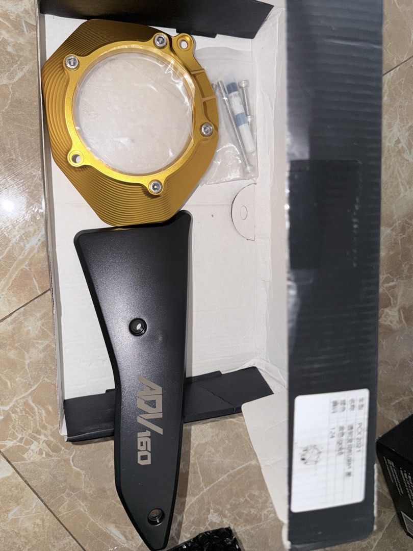 ADV 160 Motorcycle Parts (Category: Motorbikes for Sale) located in Manila. Submitted by mmgslee (Listing ID 1439049446, Image 1). Description: Listing includes motorcycle parts for the ADV 160. The set includes a gold-colored cover, a black part with "ADV 160" printed on it, and screws. The parts appear to be new and unused, still in their original packaging..