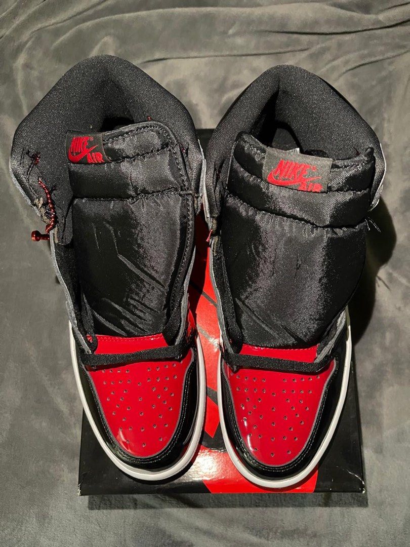 Air Jordan 1 Patent Bred (Category: Sneakers) located in Pasig City. Submitted by clairedaniellett (Listing ID 1438925018, Image 2). Description: - Air Jordan 1 Patent Bred sneakers - Black and red colorway - Patent leather finish - Nike swoosh and Air Jordan logo - Comes with original box - White midsole, red outsole.