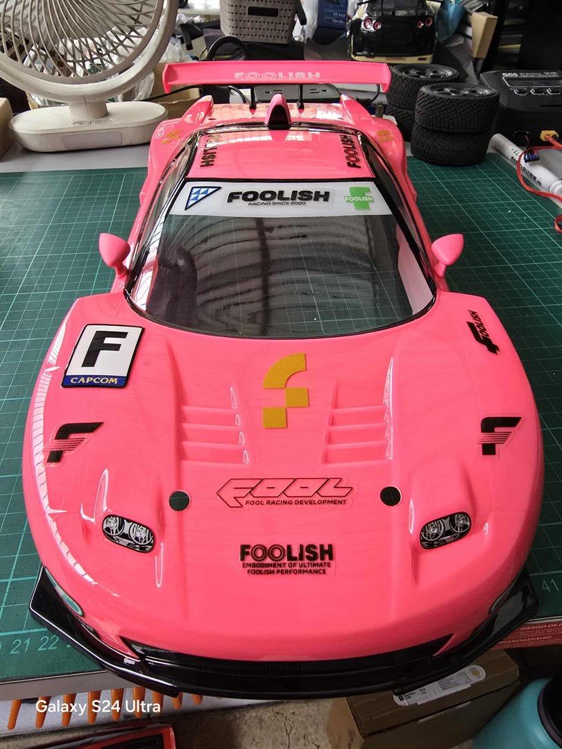 Foolish Racing RC Car Body for 1/10 scale (Category: Vehicle & Diecast Models) located in Quezon City. Submitted by notsrcph (Listing ID 1438984327, Image 3). Description: - Pink RC car body - Foolish Racing decals - Includes decals for Fool Racing Development and Capcom - Features a large rear wing - Detailed graphics - Sleek design with clear windshield and side vents - Designed for RC car use - 190mm .