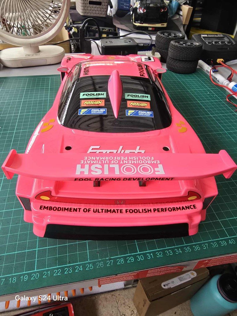 Foolish Racing RC Car Body for 1/10 scale (Category: Vehicle & Diecast Models) located in Quezon City. Submitted by notsrcph (Listing ID 1438984327, Image 2). Description: - Pink RC car body - Foolish Racing decals - Includes decals for Fool Racing Development and Capcom - Features a large rear wing - Detailed graphics - Sleek design with clear windshield and side vents - Designed for RC car use - 190mm .