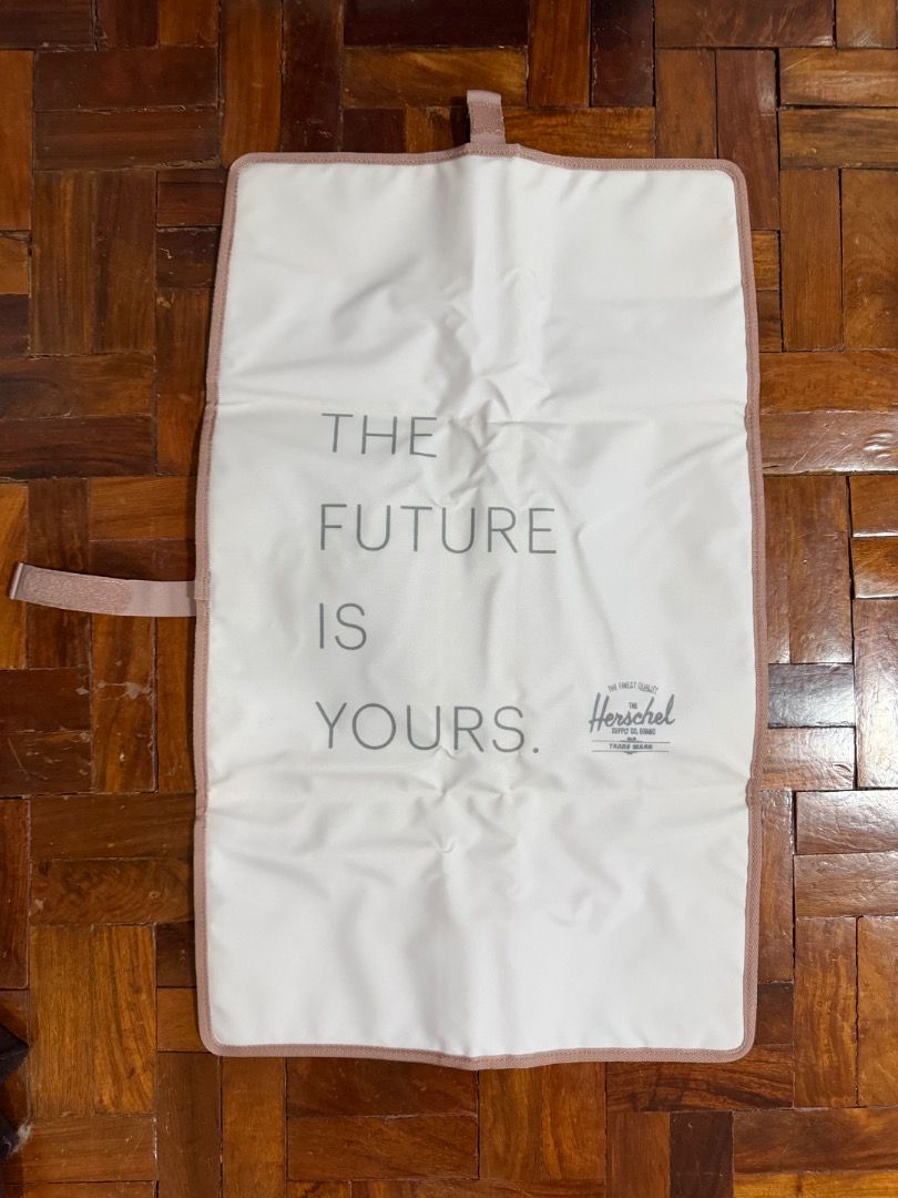 Herschel Changing Mat (Category: Changing Mats & Accessories) located in Manila. Submitted by creamsandnudes (Listing ID 1438995437, Image 3). Description: - Herschel changing mat for convenient diaper changes. - Soft, padded interior for baby's comfort. - Features the inspiring message "THE FUTURE IS YOURS." - Folds compactly and secures with a strap. - Stylish and practical for parents. - Neutral color suitable for any baby..