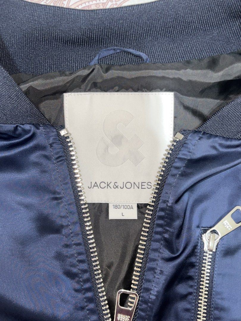 Jack & Jones Bomber Jacket (Category: Coats, Jackets and Outerwear) located in Belison. Submitted by prelovedbyellery (Listing ID 1439002443, Image 3). Description: - Navy blue bomber jacket - Zip-up front - Ribbed collar, cuffs, and hem - Two front pockets - Small pocket on left sleeve - Satin-like finish.