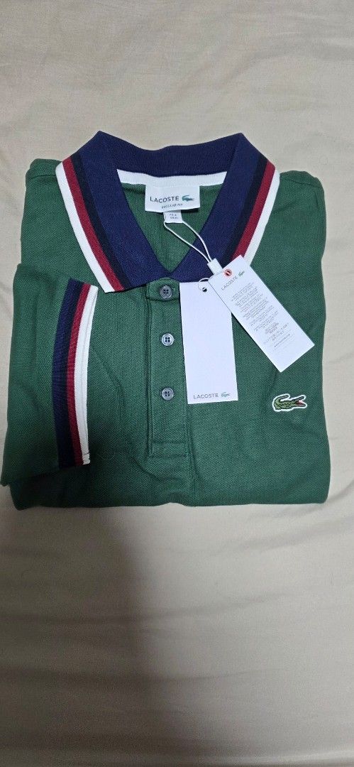 Lacoste Green Polo Shirt (Category: Tshirts & Polo Shirts ) located in Quezon City. Submitted by yGGGG (Listing ID 1439038233, Image 1). Description: - Brandnew Authentic Lacoste polo shirt - Color: Green - Classic collar with navy, red, and white stripes - Small Lacoste logo on chest - Striped sleeve cuffs - Includes original tags - Style: PH3461 - Size: Regular fit 4 Medium - Dimes: 20x27inches .