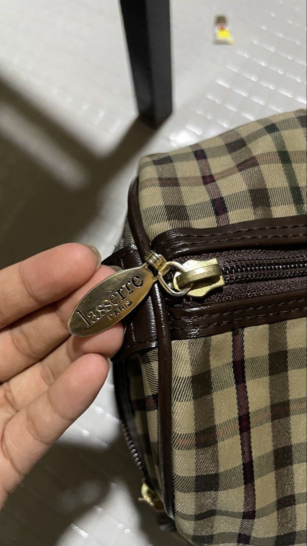 Lasserre Paris Handbag (Category: Luxury Bags & Wallets) located in Quezon City. Submitted by el_closets (Listing ID 1439010203, Image 3). Description: ARCHIVED LASSERRE PARIS VINTAGE CHECKERED BOSTON WEEKEND TRAVEL BAG MEASUREMENTS: 📏33.5 CM X 20 CM X 17 CM CONDITION USED 8/10 - Lasserre Paris handbag - Checkered pattern - Brown leather accents (handles & trim) - Zipper closure - Gold-toned logo .