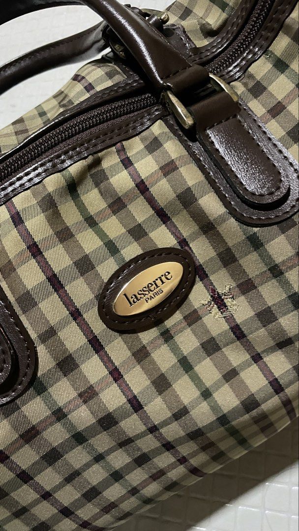 Lasserre Paris Handbag (Category: Luxury Bags & Wallets) located in Quezon City. Submitted by el_closets (Listing ID 1439010203, Image 1). Description: ARCHIVED LASSERRE PARIS VINTAGE CHECKERED BOSTON WEEKEND TRAVEL BAG MEASUREMENTS: 📏33.5 CM X 20 CM X 17 CM CONDITION USED 8/10 - Lasserre Paris handbag - Checkered pattern - Brown leather accents (handles & trim) - Zipper closure - Gold-toned logo .