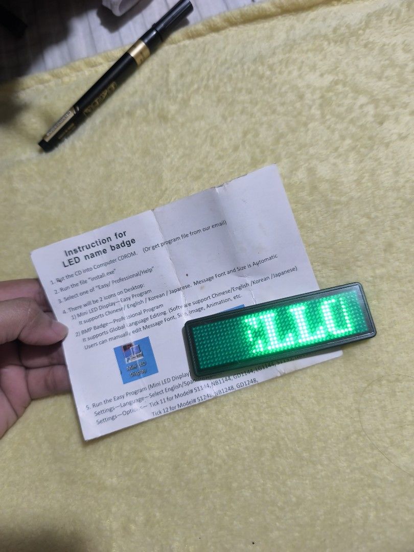 LED Name Badge (Category: Stationery & School Supplies) located in Taguig. Submitted by juliestjuly (Listing ID 1438922049, Image 1). Description: - LED name badge for displaying custom messages. - Supports multiple languages: English, Chinese, and Korean. - Programmable via computer. - Features animation display. - Comes with instructions for easy setup and use. - Green grid display..