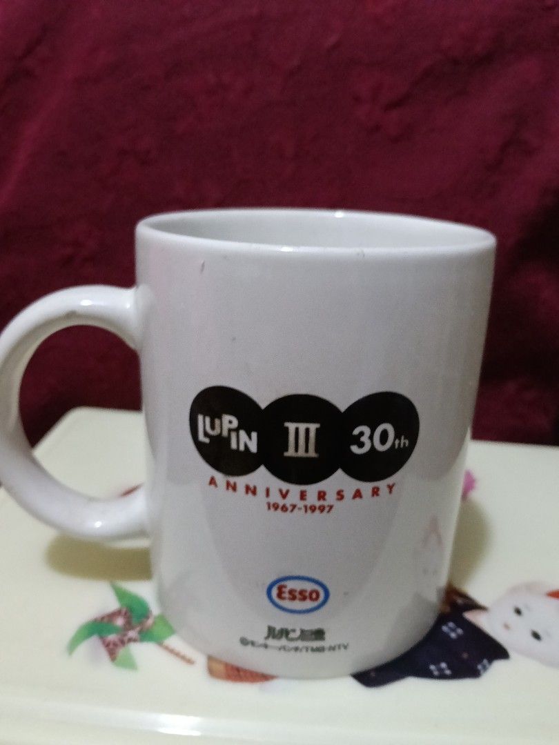 Lupin III 30th Anniversary Mug (Category: Coffee & Tea Tableware) located in Caloocan City. Submitted by jeenbeebiz (Listing ID 1438929399, Image 2). Description: - Collectible Lupin III mug. - Features Lupin III and a woman design. - Includes the Lupin III 30th Anniversary logo. - Also has the Esso logo. - White mug with a handle. - Perfect for anime fans..