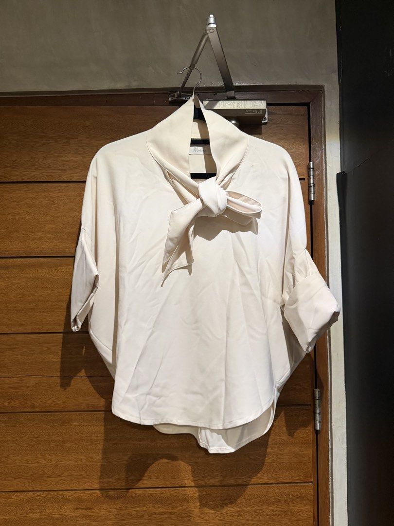 Mosaic Blouse with Tie Detail (Category: Blouses) located in Del Monte. Submitted by declutteringproject (Listing ID 1438960789, Image 1). Description: - Cream-colored blouse - Unique tie detail at neckline - Relaxed fit - Three-quarter sleeves - Smooth, satin-like fabric - Versatile for casual and semi-formal occasions.