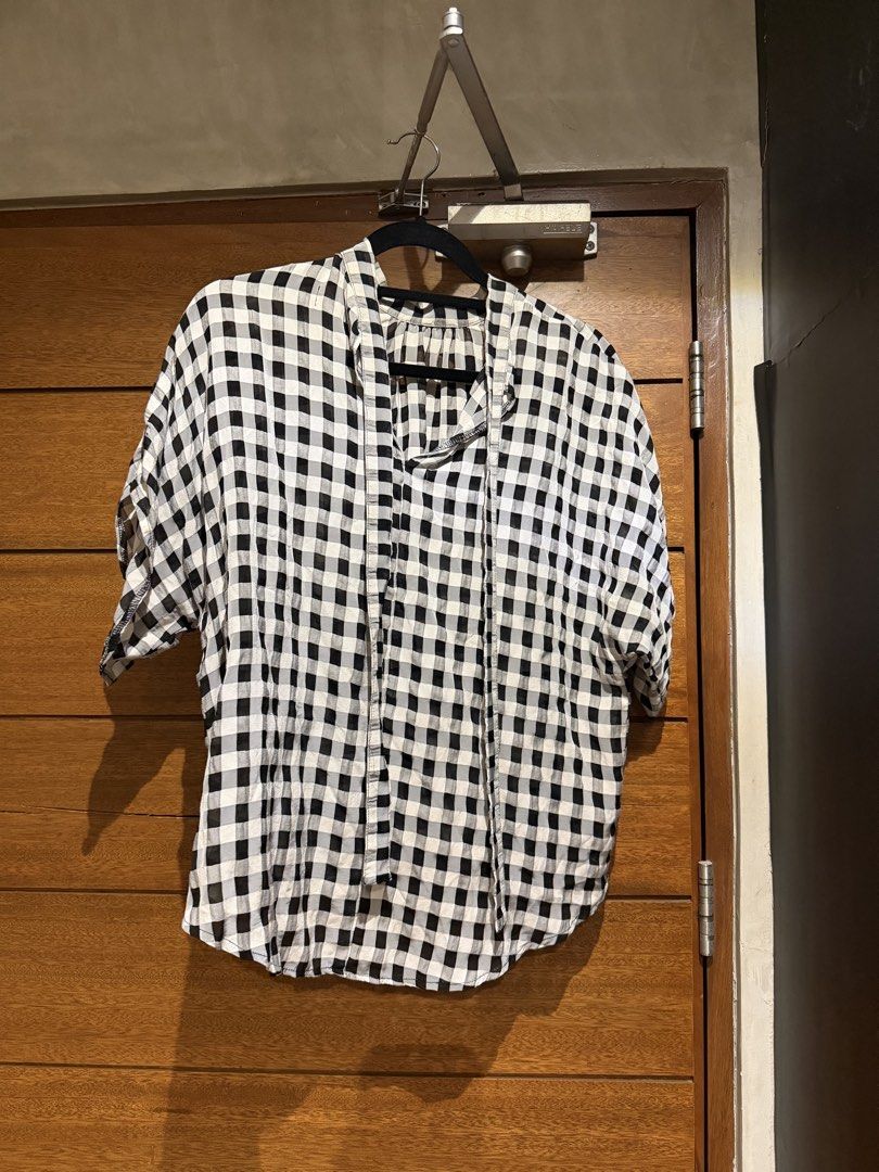 Mosaic Checkered Blouse (Category: Blouses) located in Del Monte. Submitted by declutteringproject (Listing ID 1438960381, Image 1). Description: - Classic black and white checkered pattern - Short sleeves - Relaxed fit - Collared neckline - Button-down front - Perfect for casual wear - Versatile style.