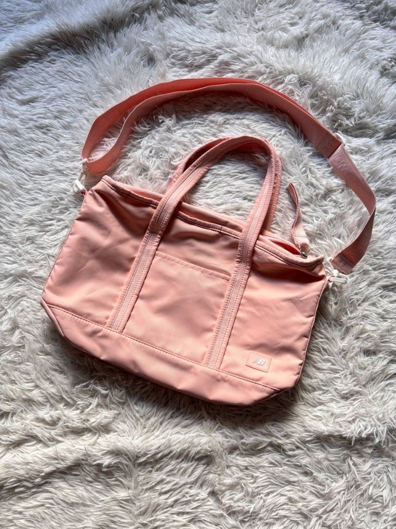 New Balance Pink Tote Bag (Category: Tote Bags) located in Catbalogan. Submitted by kristinapi (Listing ID 1438935675, Image 2). Description: Color rate: 10/10 Condition: EXCELLENT TO NEW - New Balance tote bag in a charming pink color. - Main compartment with secure zipper closure. - Includes an internal pocket for organization. - Versatile carrying options: adjustable shoulder strap and dual top handles. - Showcases the iconic New Balance logo.