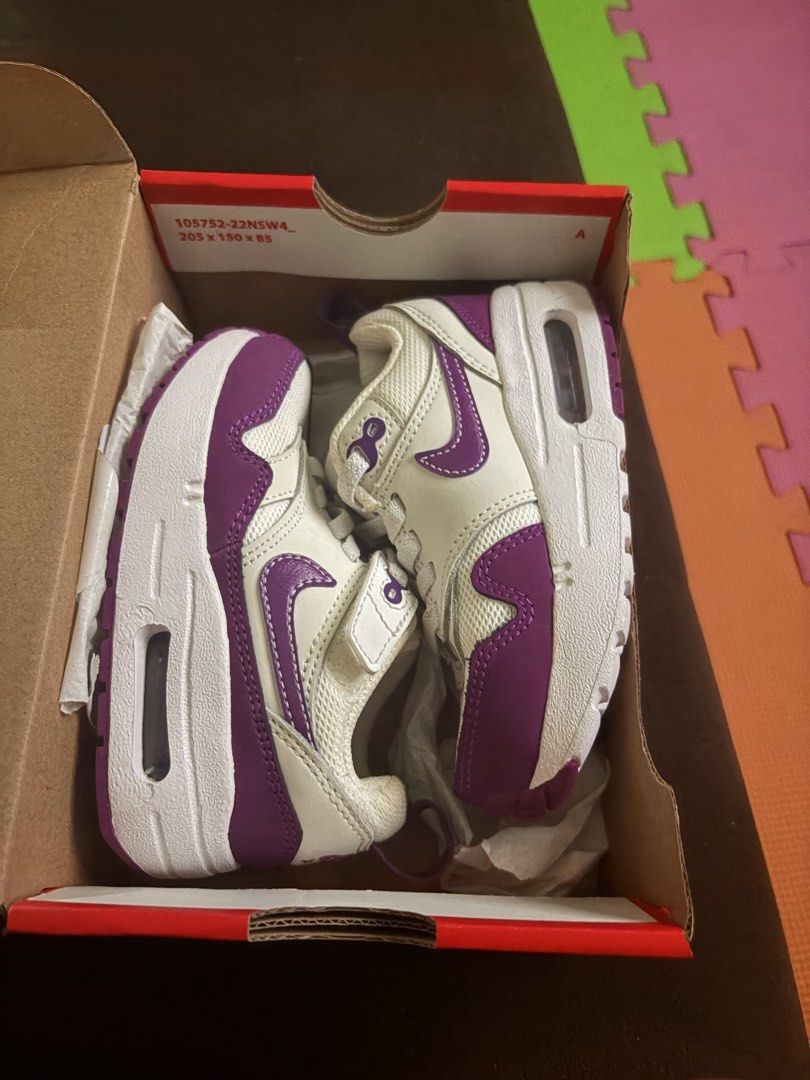 Nike Air Max 1 Easyon (PS) - 8C (Category: Babies & Kids Fashion) located in San Pedro. Submitted by AuthenticBrandedItems (Listing ID 1438968050, Image 2). Description: - Nike Air Max 1 Easyon (PS) sneakers - Color: White and Purple - Size: 8C - Easy-on design with hook-and-loop strap - Features Nike logo on side and tongue - Includes original box with Nike logo.