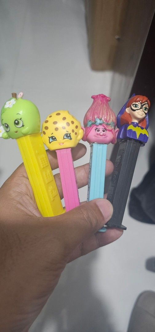 PEZ Dispensers - Assorted Characters (Category: Figurines & Statues) located in Las Pinas. Submitted by xenoraine (Listing ID 1438968183, Image 1). Description: - PEZ dispenser collection featuring: - Batgirl - Trolls character - Shopkins character - Green apple character - Each dispenser has a different colored base. - See the hand-held photo for size and design reference..