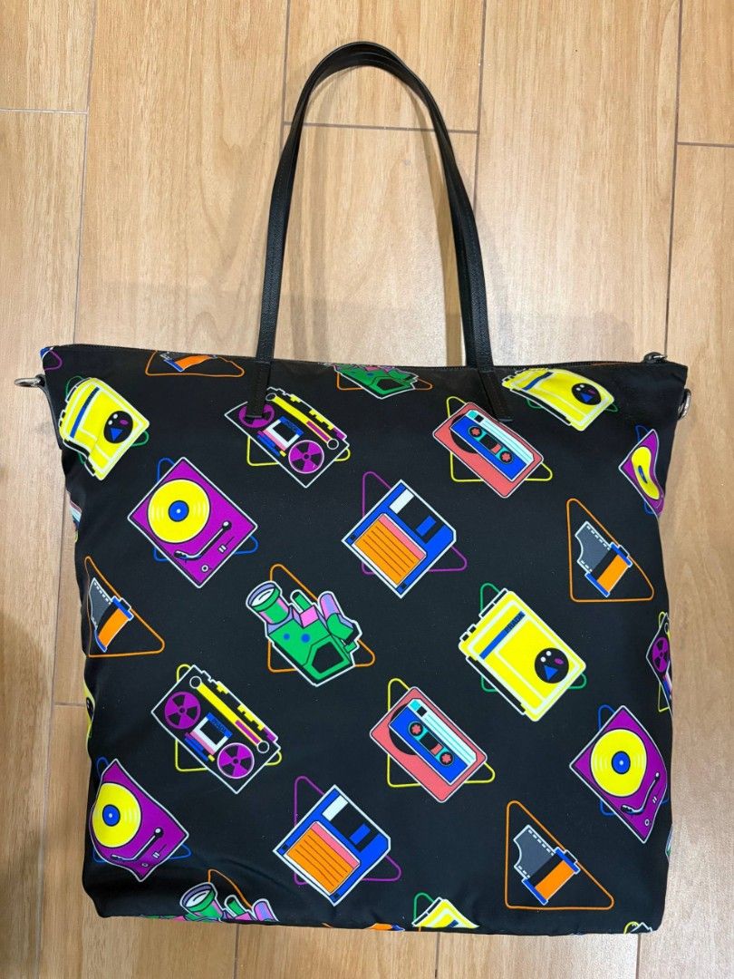 Prada Cassette Print Black Nylon Tote Bag (Category: Luxury Bags & Wallets) located in Mandaluyong City. Submitted by kimberlygo (Listing ID 1438897264, Image 2). Description: - Prada tote bag with cassette print design - Black leather handles - Secure zipper closure - Includes authenticity cards - Durable nylon exterior - Features retro cassette tapes and turntable images.