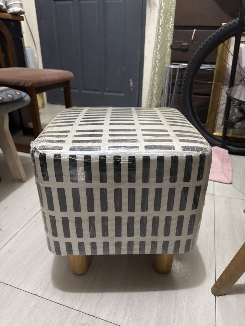 Square Footstool with Wooden Legs (Category: Chairs) located in Quezon City. Submitted by elektra0111 (Listing ID 1439000556, Image 1). Description: - Square footstool - Black and white geometric pattern - Wooden legs - Wrapped in plastic - Comfortable and functional - Perfect for resting feet or extra seating.