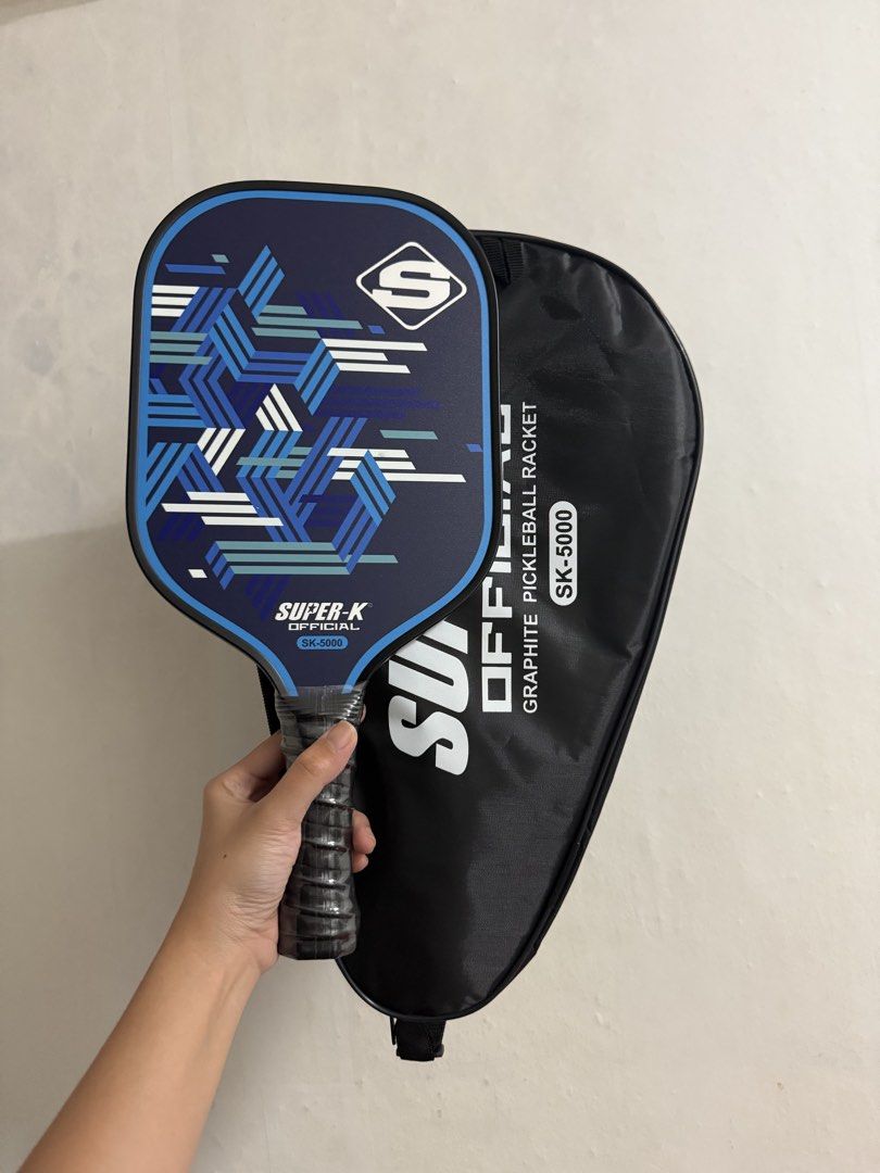 Super-K Official SK-5000 Graphite Pickleball Paddle (Category: Racket and Ball Sports) located in Manila. Submitted by myleeybanez (Listing ID 1439024875, Image 2). Description: - Super-K SK-5000 pickleball paddle - Graphite construction - Stylish blue and white geometric design - Comfortable black grip - Includes a protective case - Case features Super-K logo and model number - Good for beginners MOP: Bank Transfer/Gcash Location: Makati/Malate 