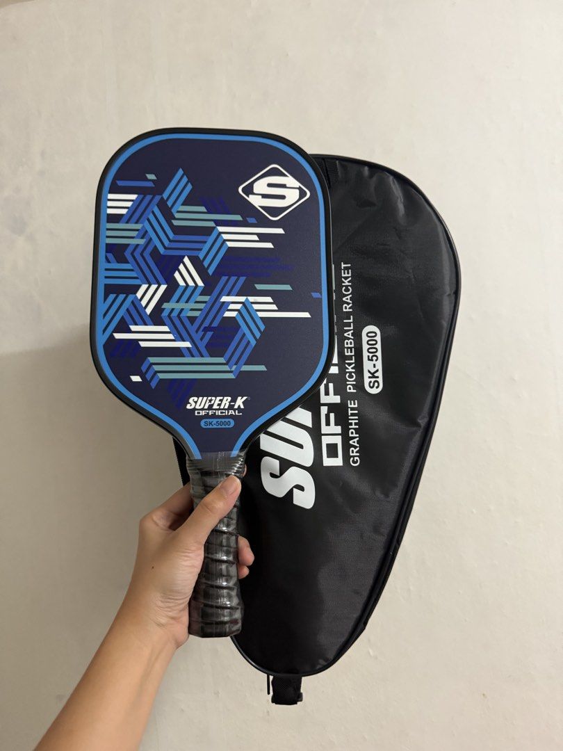 Super-K Official SK-5000 Graphite Pickleball Paddle (Category: Racket and Ball Sports) located in Manila. Submitted by myleeybanez (Listing ID 1439024875, Image 3). Description: - Super-K SK-5000 pickleball paddle - Graphite construction - Stylish blue and white geometric design - Comfortable black grip - Includes a protective case - Case features Super-K logo and model number - Good for beginners MOP: Bank Transfer/Gcash Location: Makati/Malate 