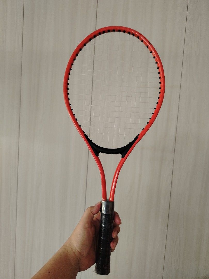 Tennis Racket for kids (Category: Racket and Ball Sports) located in Tayasan. Submitted by _raceprettyconcept (Listing ID 1438914597, Image 1). Description: - orange tennis racket with black grip - Strings are intact - Standard size - for kids - Red frame with black accents.