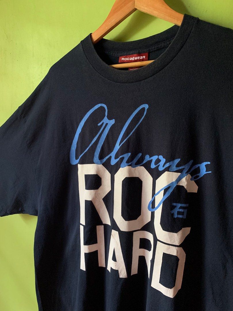 Vintage late 1990s Rocawear tee (Category: Tshirts & Polo Shirts ) located in Cagayan de Oro. Submitted by premium_thrifts (Listing ID 1438909168, Image 2). Description: Navy blue colorway. Good condition. Issues: slight crackprint, spot stains on print, and fades on collar - MEASUREMENTS: L32.5" x W25" 24.5" (shoulder to shoulder) 9.5" (sleeve length) Fits 2XL Add shipping fee (via JRS or J&T).
