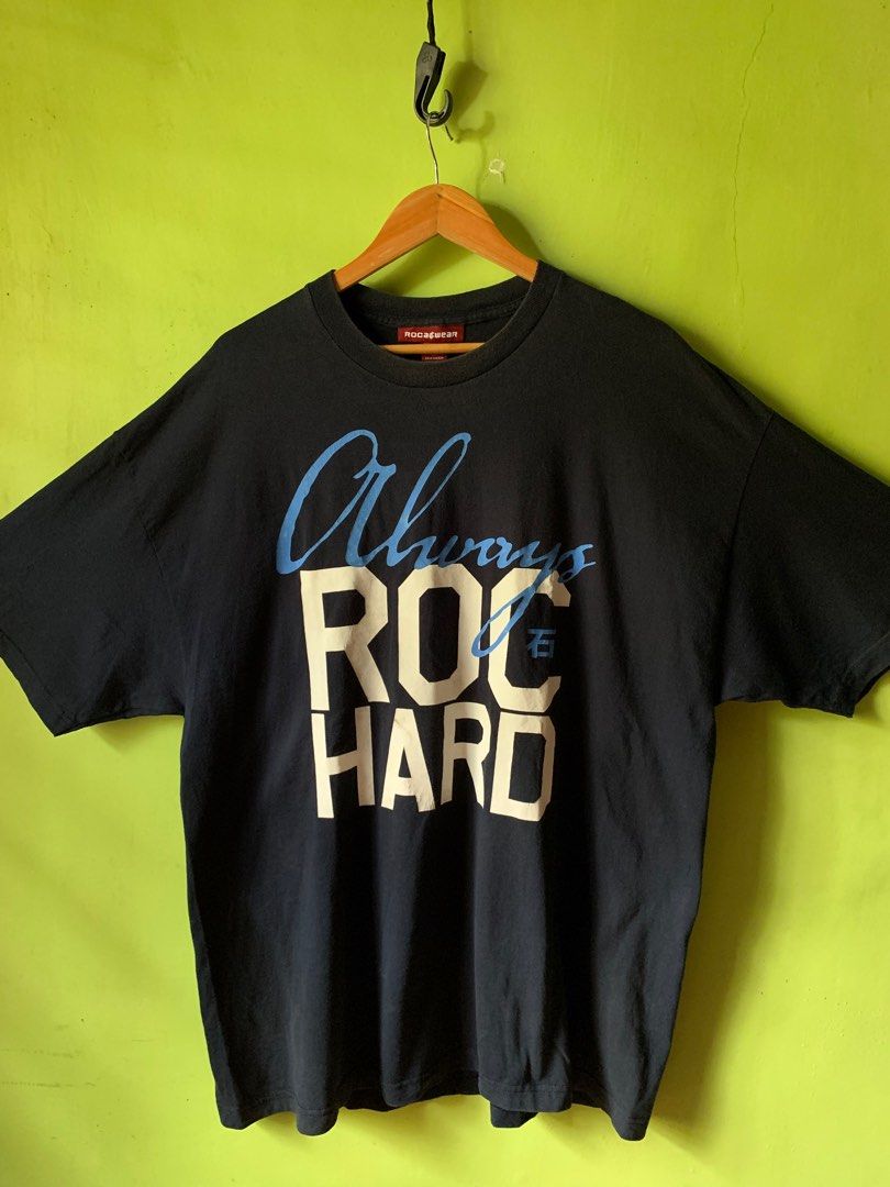 Vintage late 1990s Rocawear tee (Category: Tshirts & Polo Shirts ) located in Cagayan de Oro. Submitted by premium_thrifts (Listing ID 1438909168, Image 1). Description: Navy blue colorway. Good condition. Issues: slight crackprint, spot stains on print, and fades on collar - MEASUREMENTS: L32.5" x W25" 24.5" (shoulder to shoulder) 9.5" (sleeve length) Fits 2XL Add shipping fee (via JRS or J&T).