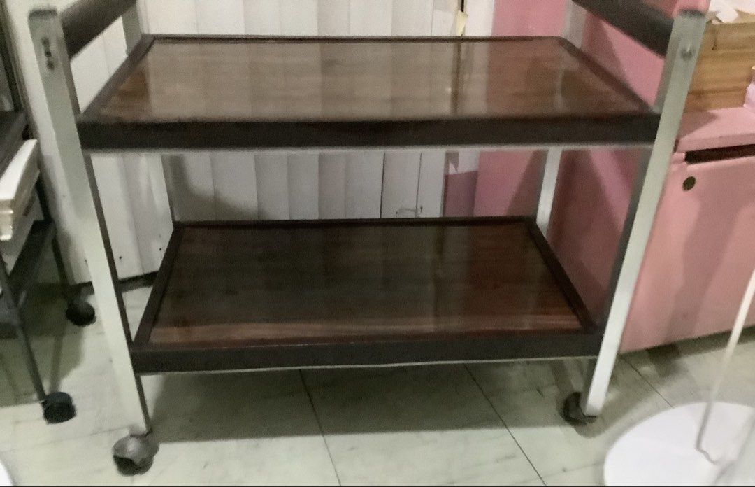 Vintage Serving Cart with Wheels (Category: Other Home Furniture) located in Manila. Submitted by jamecy (Listing ID 1439000308, Image 1). Description: - Vintage serving cart - Two wooden shelves with dark finish - Metal frame - Equipped with wheels for easy mobility - Ideal for serving drinks and snacks - Great for displaying items - Classic design suitable for various interiors.