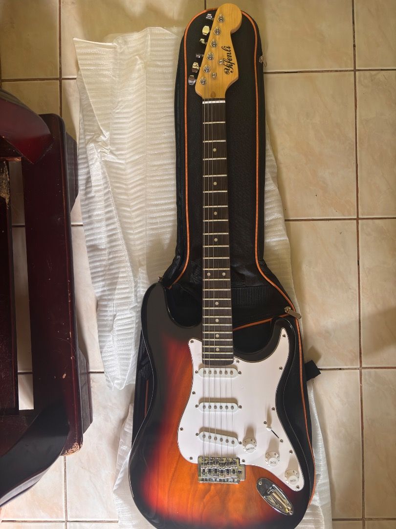YIFENLI Electric Guitar with Case (Category: Musical Instruments) located in Caloocan City. Submitted by blackstar1019 (Listing ID 1438881003, Image 1). Description: 39 inch Electric Guitar ST Electric Guitar Telecaster w/ accesories - Sunburst finish - White pickguard - Three pickups - Tremolo bridge - Includes a black guitar case with orange trim - Comes with a cable - Brand new in original packaging.