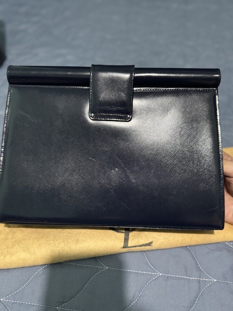 Yves Saint Laurent Navy Clutch (Category: Luxury Bags & Wallets) located in Manila. Submitted by vera26 (Listing ID 1439015183, Image 2). Description: - Yves Saint Laurent navy clutch - Gold-tone clasp with YSL branding - Includes dust bag - Interior: Patterned lining with YSL logo - Shape: Rectangular - Closure: Flap - Exterior: Smooth material with minimal scratches.