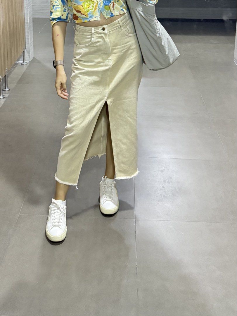Zara Beige Denim Slit Skirt (Category: Skirts) located in Las Pinas. Submitted by shopnshopperph (Listing ID 1439009471, Image 1). Description: - Beige denim midi skirt - Front slit detail - Raw hem - Classic five-pocket design - Button and zipper closure - Sturdy denim material - Versatile for various outfits.