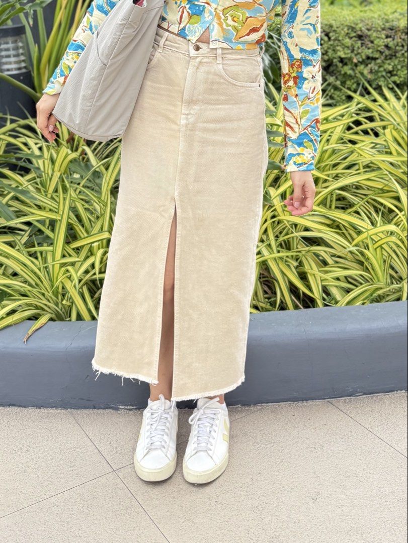 Zara Beige Denim Slit Skirt (Category: Skirts) located in Las Pinas. Submitted by shopnshopperph (Listing ID 1439009471, Image 2). Description: - Beige denim midi skirt - Front slit detail - Raw hem - Classic five-pocket design - Button and zipper closure - Sturdy denim material - Versatile for various outfits.