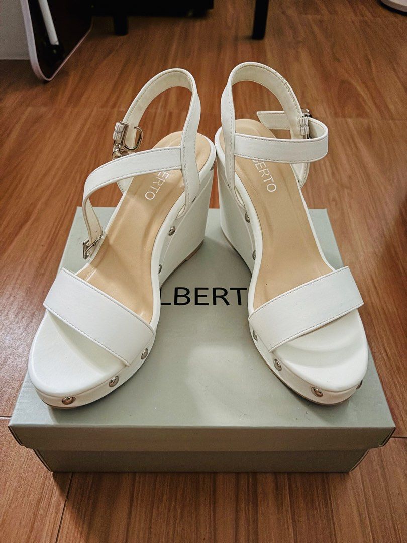 Alberto Claire White Wedge Sandals (Category: Sandals) located in Cavite. Submitted by MalynHey (Listing ID 1439114860, Image 1). Description: - Alberto Claire wedge sandals - Size: 37 EU / 6 US - Color: White - Features: Buckle closure, silver studs - Condition: Unworn - Includes original box.