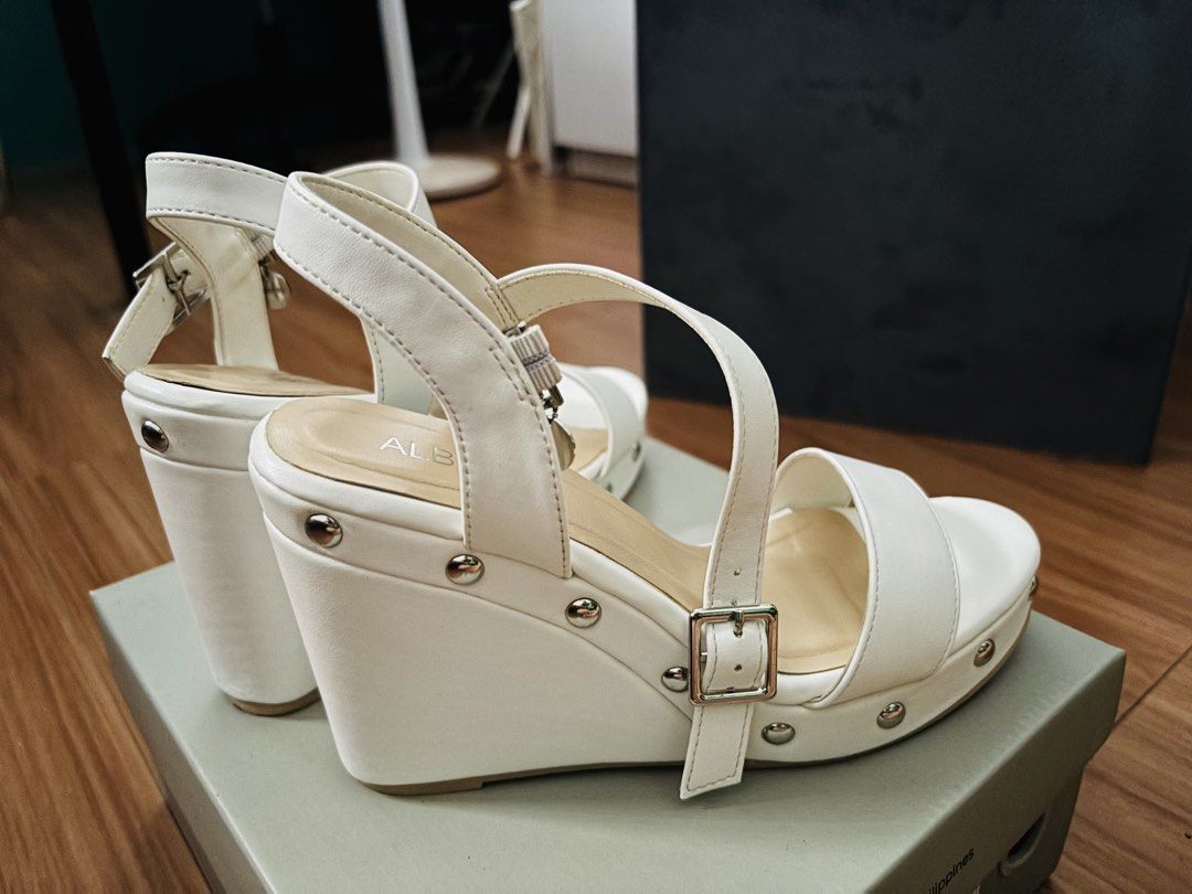 Alberto Claire White Wedge Sandals (Category: Sandals) located in Cavite. Submitted by MalynHey (Listing ID 1439114860, Image 3). Description: - Alberto Claire wedge sandals - Size: 37 EU / 6 US - Color: White - Features: Buckle closure, silver studs - Condition: Unworn - Includes original box.