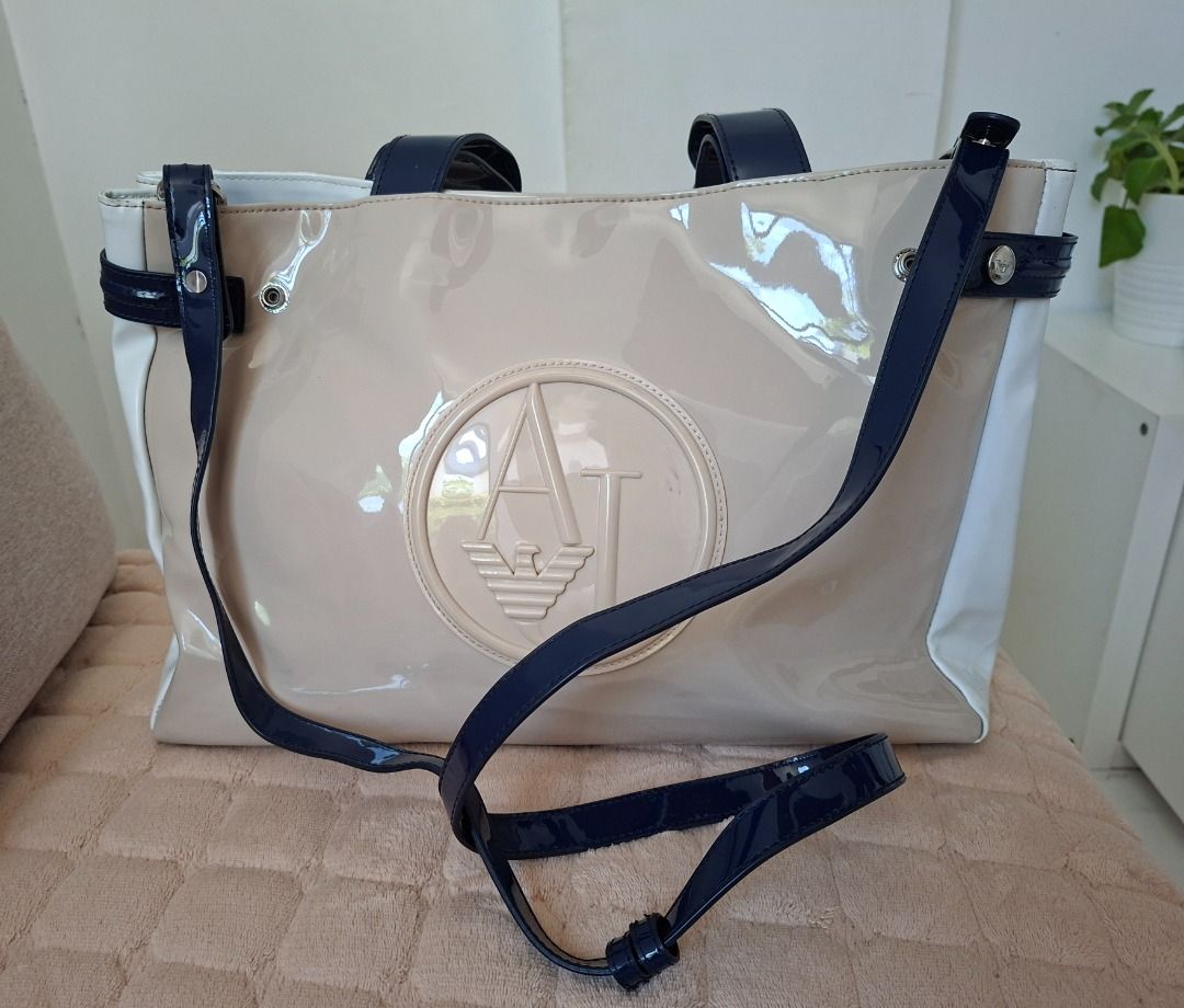 Armani Exchange Patent Tote Bag (Category: Luxury Bags & Wallets) located in Tuguegarao City. Submitted by thosphbys49295 (Listing ID 1439079044, Image 1). Description: - Armani Exchange tote bag - Beige and white patent finish - Navy blue shoulder strap and handles - Circular logo detail - Detachable shoulder strap.