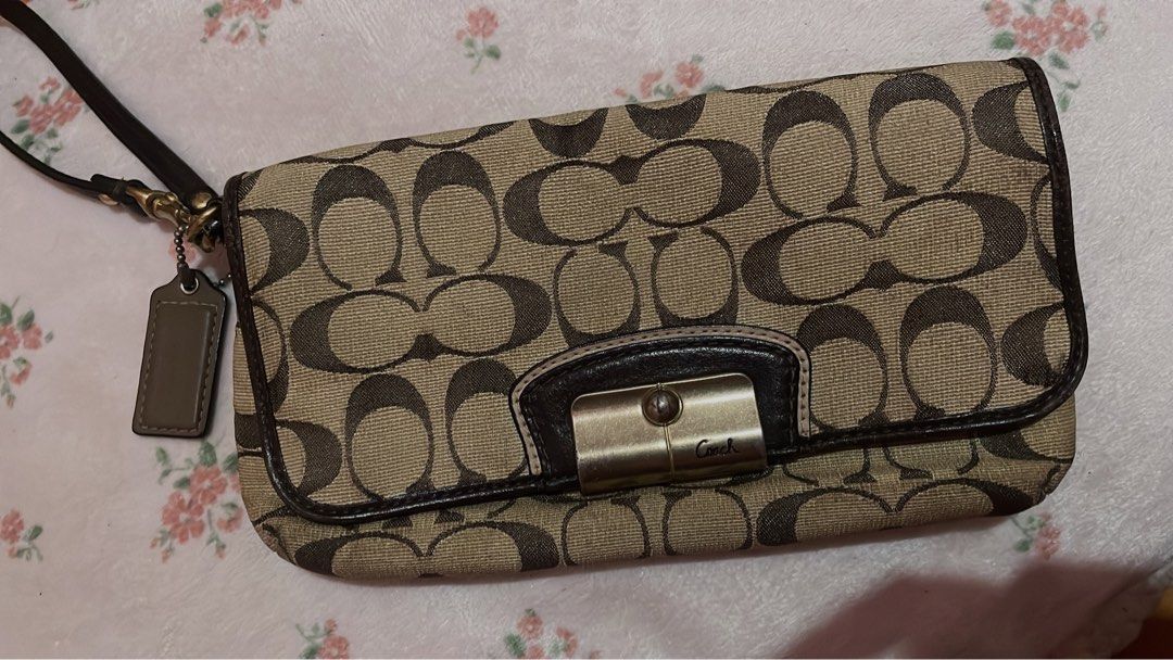 Authentic Coach Signature Turnlock Wristlet (Category: Purses & Pouches) located in Caloocan City. Submitted by ruby_welly22 (Listing ID 1439210279, Image 1). Description: Pre-loved. Canvas and interior are clean, leather strap is intact. Hardware has visible scratches/fading on the turnlock plate due to use (see photos), but it still locks perfectly. .