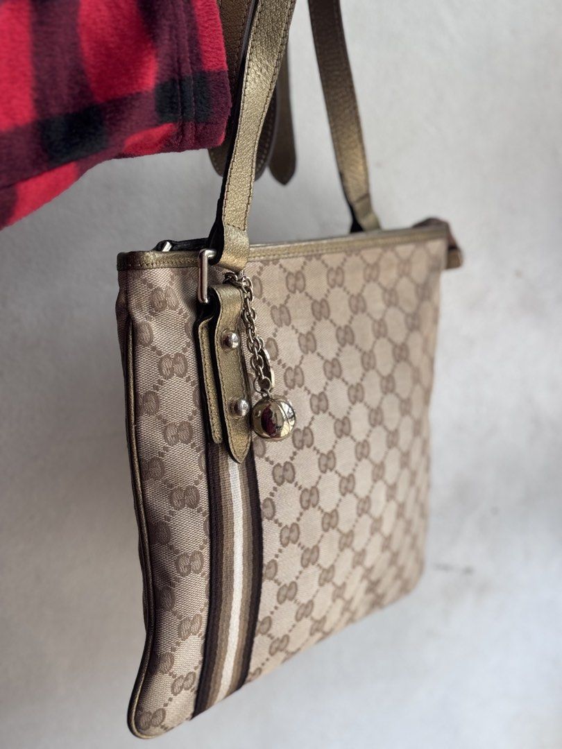 Authentic Gucci GG Canvas Crossbody Bag (Category: Luxury Bags & Wallets) located in Manila. Submitted by thriftyhaven2023 (Listing ID 1439118561, Image 2). Description: 8/10 Condition - Authentic Gucci shoulder bag - Iconic GG canvas - Gold-toned shoulder strap and hardware - Vertical stripe detail - Includes charm with ball pendant NO FLAWS Has minimal normal signs of usage only..