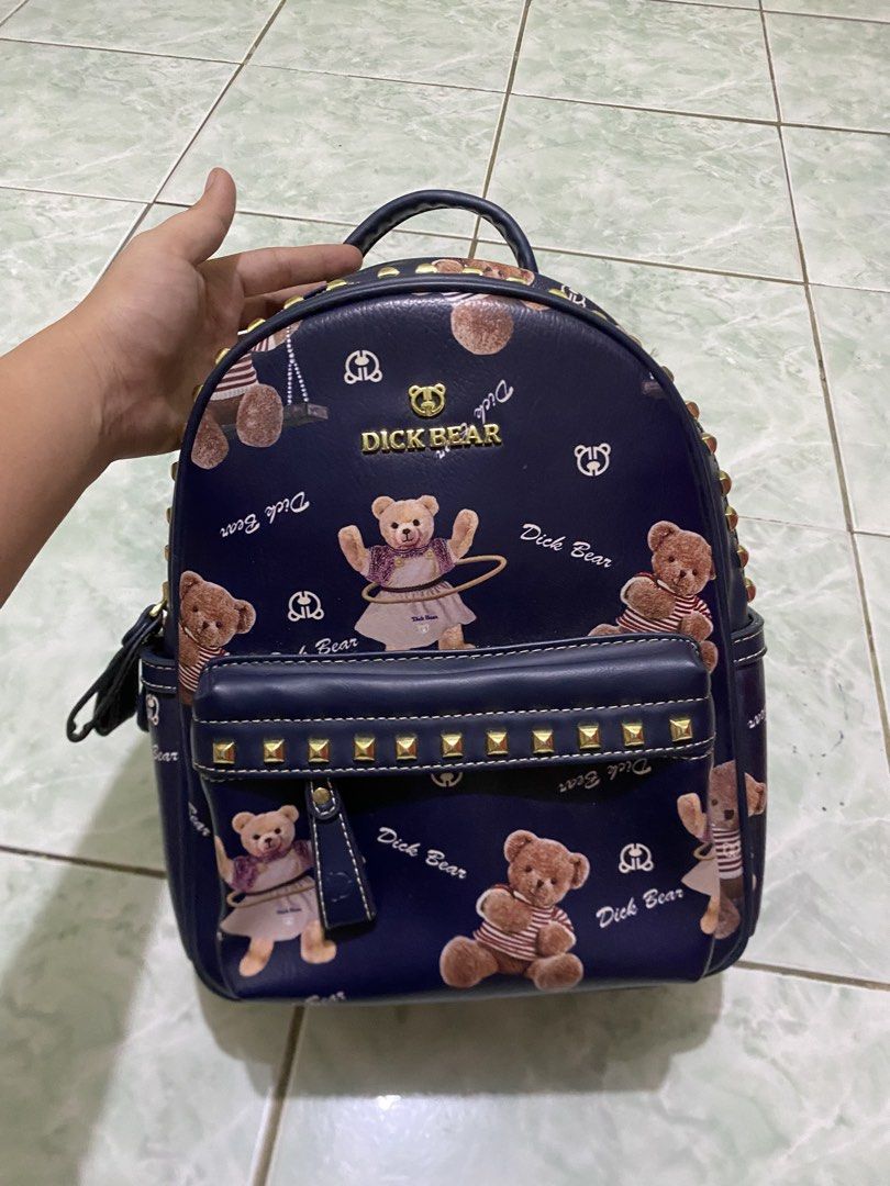 Dick Bear Teddy Bear Backpack (Category: Backpacks) located in Valenzuela. Submitted by lotbi (Listing ID 1439113660, Image 1). Description: - Navy blue backpack with adorable teddy bear print - Stylish gold-colored stud accents - Comfortable top handle and adjustable straps - Spacious interior with multiple compartments - Features a chic brown lining - Branded "Dick Bear" design on front and inside.