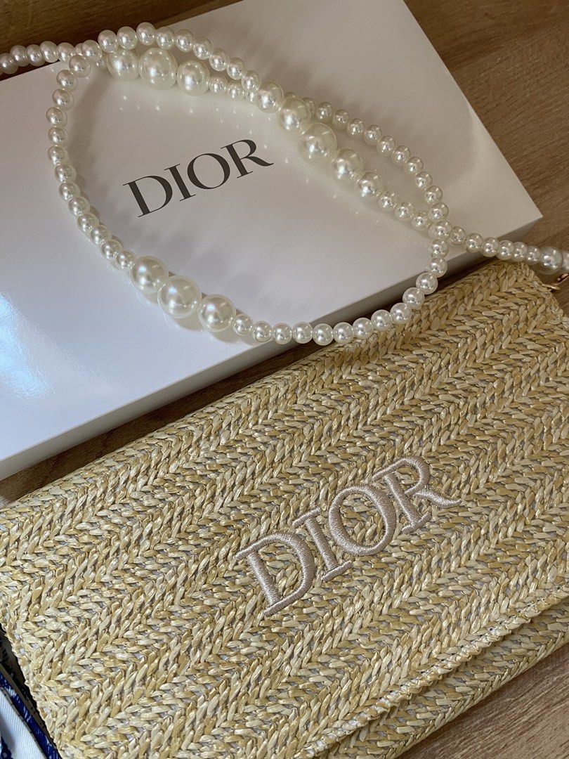 Dior Straw Clutch with Pearl Strap (Category: Luxury Bags & Wallets) located in Manila. Submitted by frish_2525 (Listing ID 1439123934, Image 2). Description: - Authentic Dior clutch - Woven straw exterior - Embroidered Dior logo - Detachable pearl strap - Includes matching box - Interior: zippered compartment and fabric lining - Comes with a small blue and white patterned accessory.