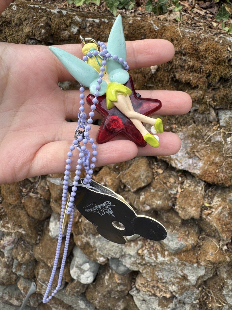 Disneyland Resort Tinkerbell Light-Up Keychain (Category: Character Goods) located in Baguio. Submitted by goodfindsbaguio (Listing ID 1439202786, Image 2). Description: Disneyland Resort keychain features Tinkerbell with a red star-shaped light-up design. It includes a purple beaded chain and a tag that says "I light up!". The keychain has a metal clasp for easy attachment. The tag shows the Disneyland Resort logo. Does not light up anymore‼️.