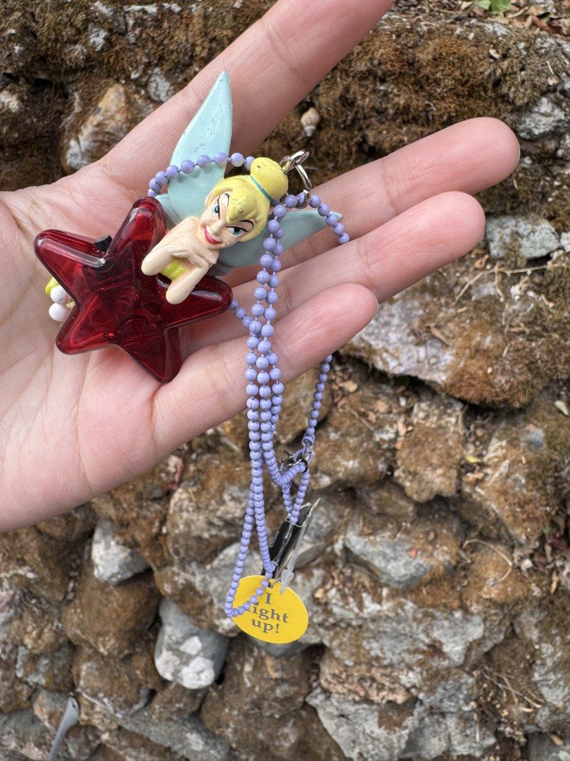 Disneyland Resort Tinkerbell Light-Up Keychain (Category: Character Goods) located in Baguio. Submitted by goodfindsbaguio (Listing ID 1439202786, Image 3). Description: Disneyland Resort keychain features Tinkerbell with a red star-shaped light-up design. It includes a purple beaded chain and a tag that says "I light up!". The keychain has a metal clasp for easy attachment. The tag shows the Disneyland Resort logo. Does not light up anymore‼️.