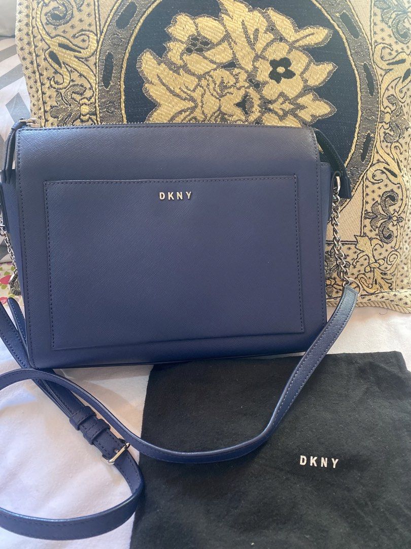 DKNY Navy Blue Crossbody Bag (Category: Cross-body Bags) located in Angeles City. Submitted by tonijojoe_owl (Listing ID 1439212271, Image 1). Description: - DKNY crossbody bag in navy blue - Front pocket for easy access - Adjustable long strap for shoulder or crossbody wear - Includes a dust bag for storage - Features a stylish silver DKNY logo - Made of smooth material.