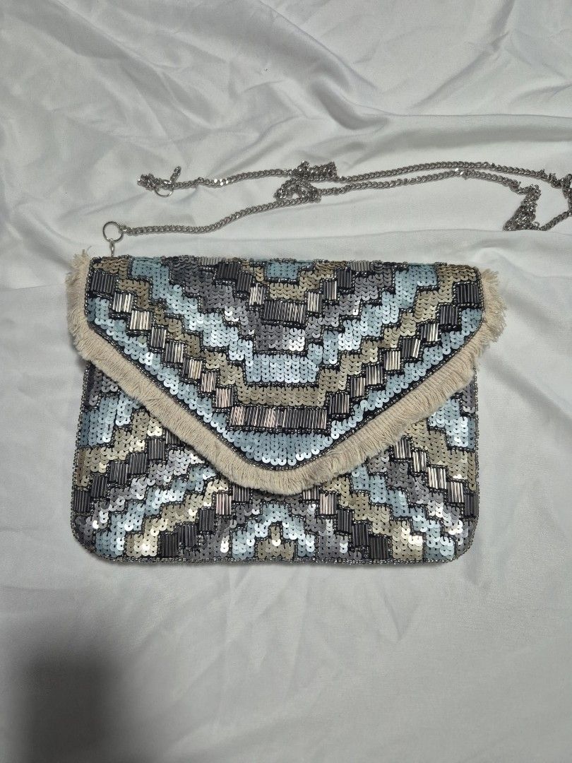 Embellished Clutch Bag with Chain Strap (Category: Clutches) located in Cainta. Submitted by mintandcinnamon (Listing ID 1439200382, Image 2). Description: Bought from @alexrosecairo, found her in IG. only used once, selling for 1500 - Intricate sequin and bead design - Detachable chain strap; chain's other end is already broken but can be replaced easily - Flap closure - Includes a blue drawstring dust bag - Color palette: Blue, silver, and beig