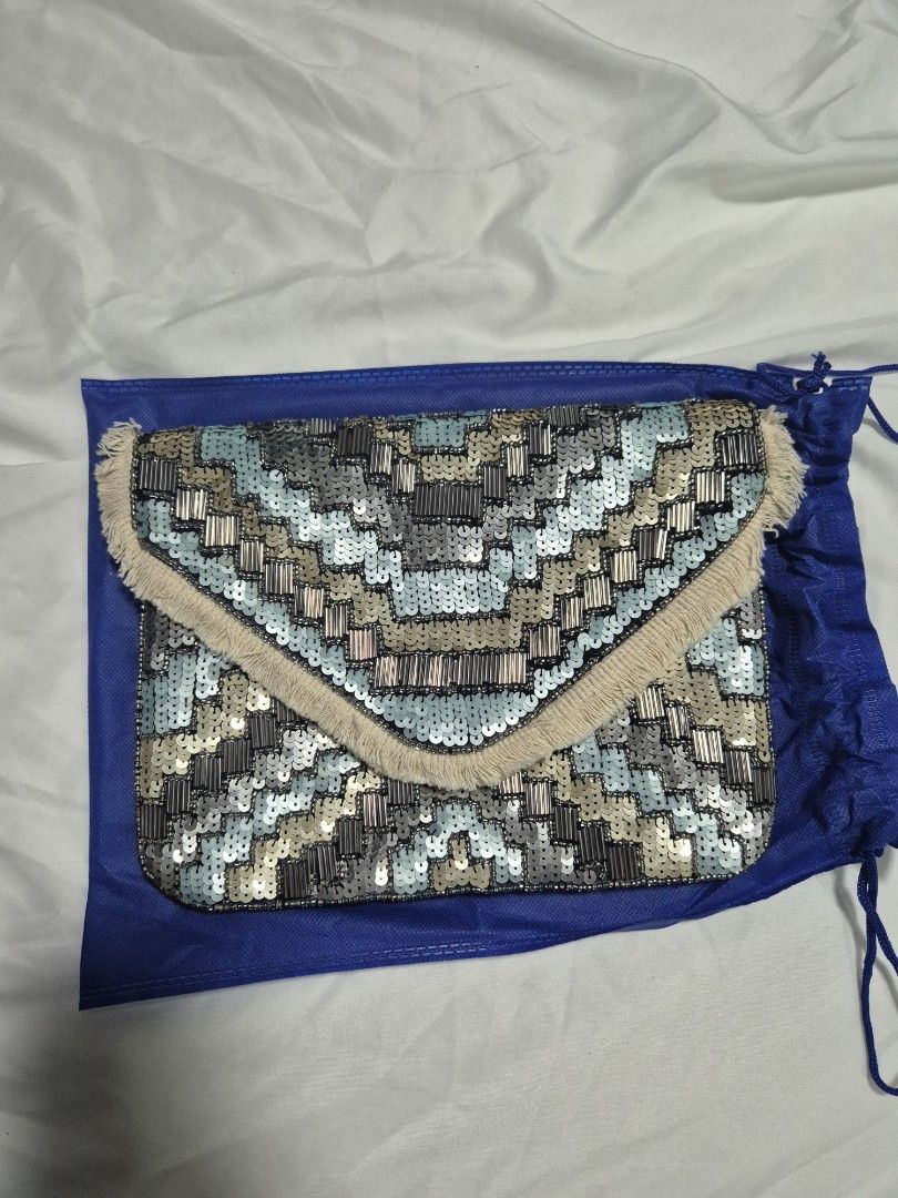 Embellished Clutch Bag with Chain Strap (Category: Clutches) located in Cainta. Submitted by mintandcinnamon (Listing ID 1439200382, Image 1). Description: Bought from @alexrosecairo, found her in IG. only used once, selling for 1500 - Intricate sequin and bead design - Detachable chain strap; chain's other end is already broken but can be replaced easily - Flap closure - Includes a blue drawstring dust bag - Color palette: Blue, silver, and beig