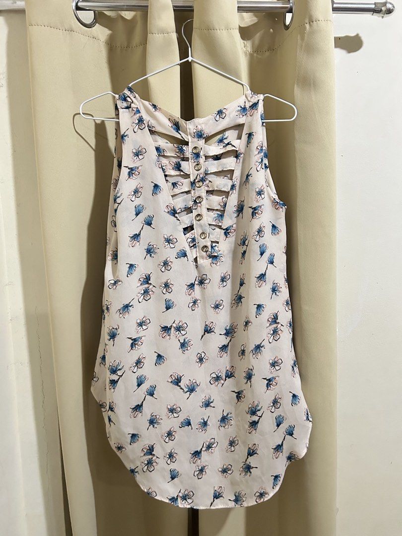 Floral Sleeveless Top (Category: Sleeveless) located in Manila. Submitted by decluttr.corner (Listing ID 1439141361, Image 2). Description: - Floral sleeveless top - Unique cut-out back design with button details - V-neckline - Curved hem - White with blue and black floral pattern - Lightweight and flowy fabric - Ideal for warm weather.