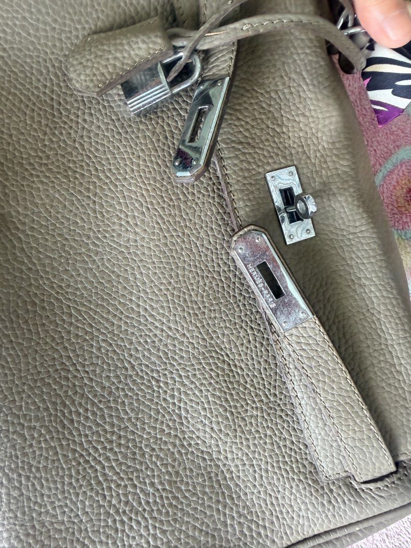 Hermes Kelly Handbag with Scarf (Category: Luxury Bags & Wallets) located in Taguig. Submitted by che_f25 (Listing ID 1439095796, Image 2). Description: - Hermes Kelly handbag (exact copy) - Neutral color, textured leather - Includes a scarf wrapped around the handle - Comes with lock and key - Spacious interior with zippered pocket - Includes dust bag - Silver-tone hardware - Classic design.