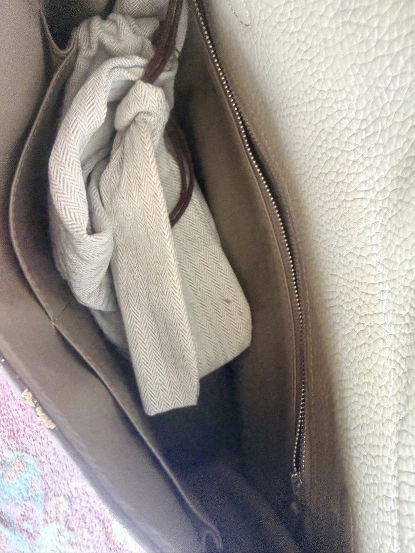 Hermes Kelly Handbag with Scarf (Category: Luxury Bags & Wallets) located in Taguig. Submitted by che_f25 (Listing ID 1439095796, Image 3). Description: - Hermes Kelly handbag (exact copy) - Neutral color, textured leather - Includes a scarf wrapped around the handle - Comes with lock and key - Spacious interior with zippered pocket - Includes dust bag - Silver-tone hardware - Classic design.