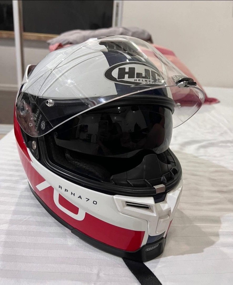 HJC RPHA 70 Motorcycle Helmet (Category: Helmets and other Riding Gears) located in Alaminos. Submitted by osaj55756 (Listing ID 1439095088, Image 2). Description: original - HJC RPHA 70 motorcycle helmet - Color: White, red, and blue - Includes clear visor - Includes dark visor - RPHA 70 model visible - Features a secure strap.