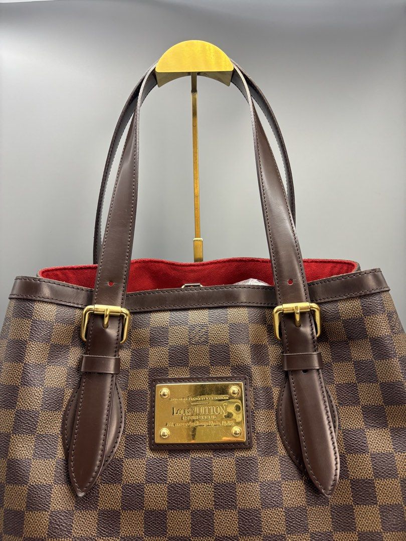 Louis Vuitton Damier Ebene Hampstead MM Handbag (Category: Luxury Bags & Wallets) located in General Trias. Submitted by pi_cl_2021 (Listing ID 1439085010, Image 2). Description: - Authentic Louis Vuitton Verona MM handbag. - Damier Ebene canvas. - Brown leather handles and trim. - Gold-tone hardware. - Red fabric interior. - Includes Louis Vuitton logo plaque. - Structured shape. - Classic check pattern..