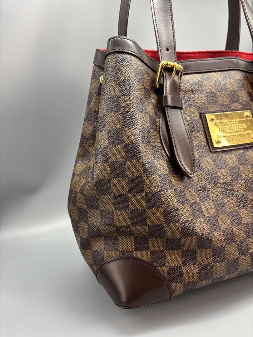 Louis Vuitton Damier Ebene Hampstead MM Handbag (Category: Luxury Bags & Wallets) located in General Trias. Submitted by pi_cl_2021 (Listing ID 1439085010, Image 3). Description: - Authentic Louis Vuitton Verona MM handbag. - Damier Ebene canvas. - Brown leather handles and trim. - Gold-tone hardware. - Red fabric interior. - Includes Louis Vuitton logo plaque. - Structured shape. - Classic check pattern..