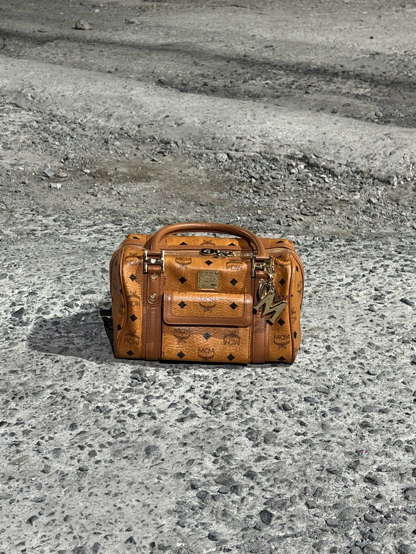 MCM Boston Bag (Category: Luxury Bags & Wallets) located in Manila. Submitted by lancephili44479 (Listing ID 1439197464, Image 2). Description: - Authentic MCM Boston bag - Features the iconic MCM logo pattern - Top handle and front pocket - Includes a gold-tone charm - Suitable for everyday use or special occasions.