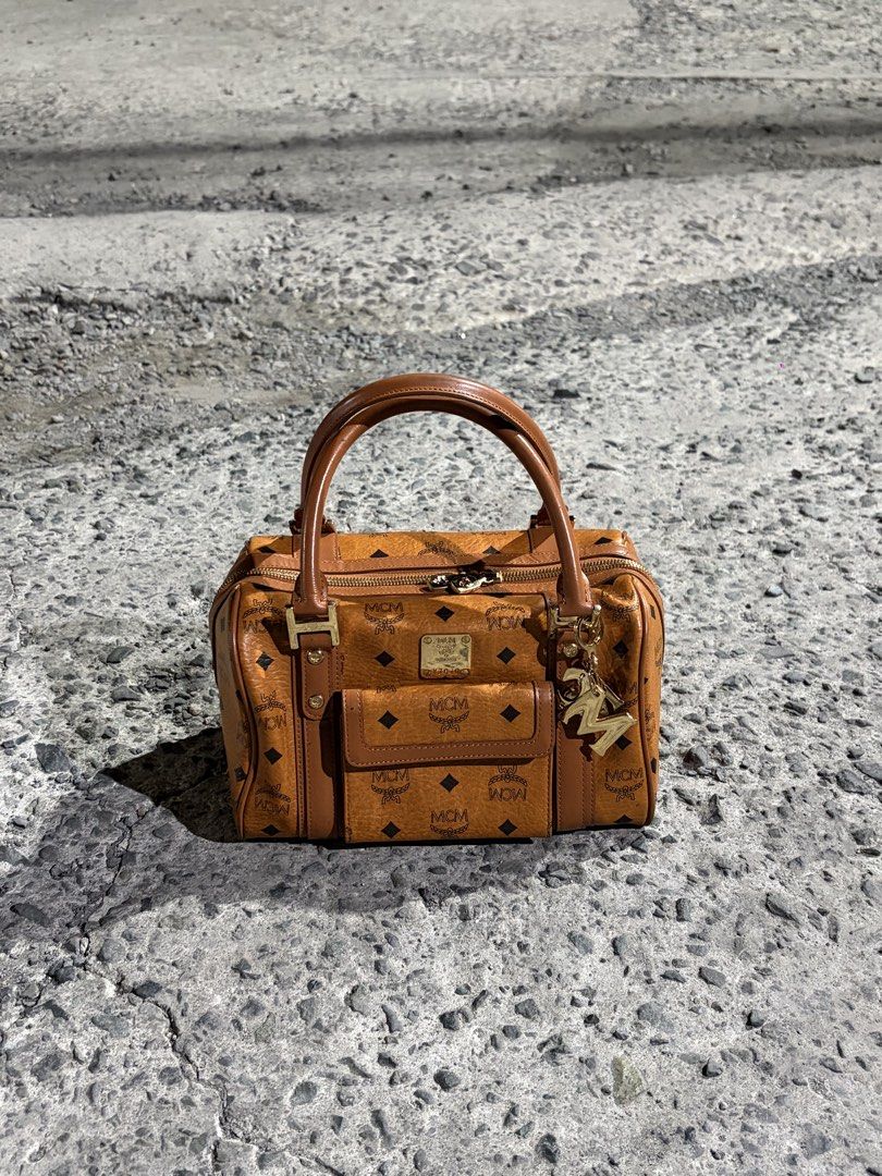 MCM Boston Bag (Category: Luxury Bags & Wallets) located in Manila. Submitted by lancephili44479 (Listing ID 1439197464, Image 3). Description: - Authentic MCM Boston bag - Features the iconic MCM logo pattern - Top handle and front pocket - Includes a gold-tone charm - Suitable for everyday use or special occasions.